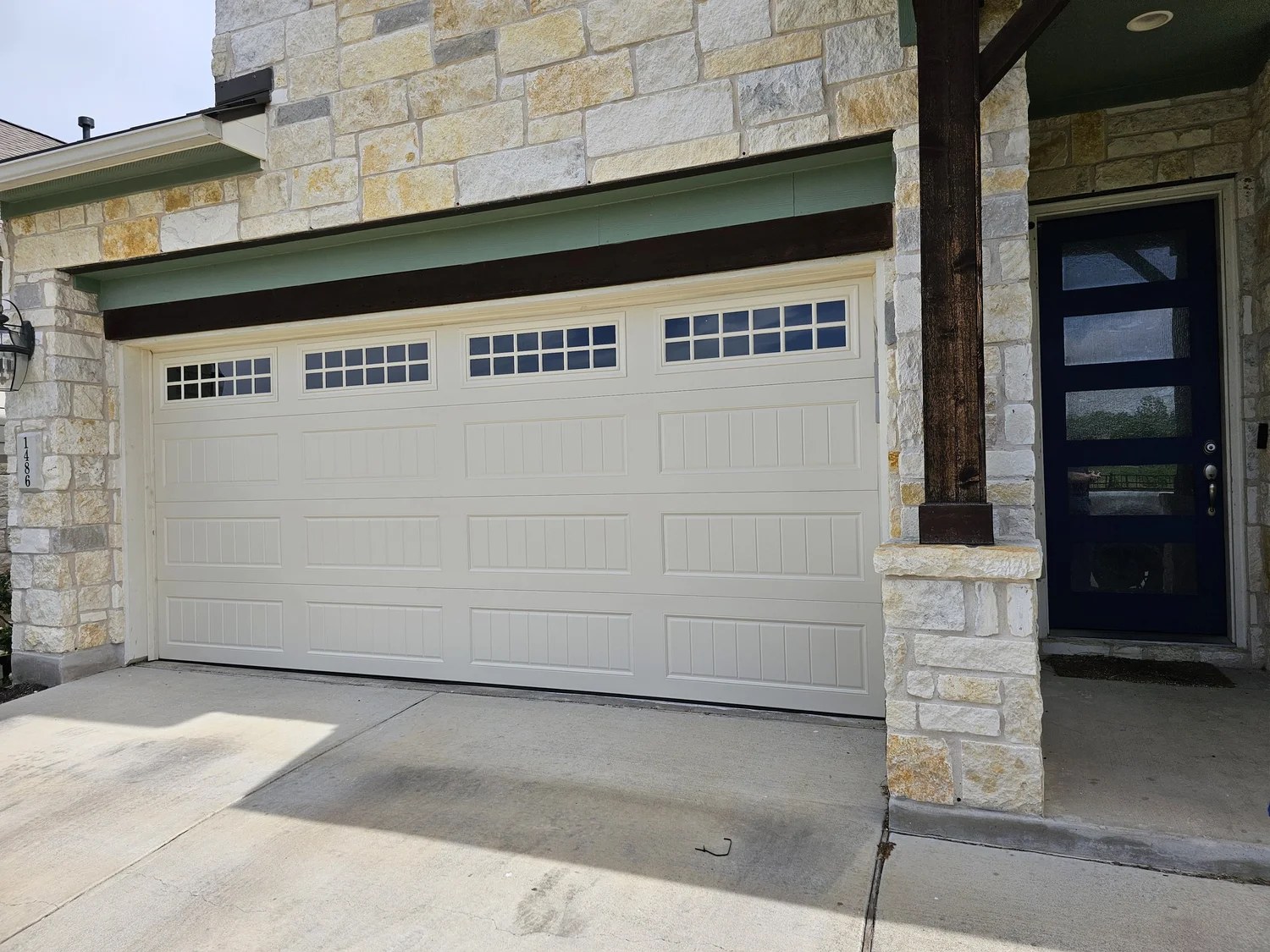 White carriage-style garage door with windows on a limestone home, from the Matamoros project portfolio